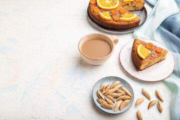 Orange cake with almonds and a cup of coffee on a white concrete background. Top view, copy space.