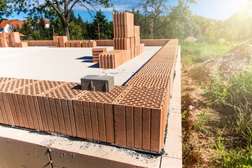 Construction site of a family house. Concrete base plate. Wall construction. Red bricks on a construction site. House construction.