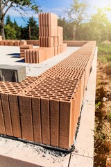 Construction site of a family house. Concrete base plate. Wall construction. Red bricks on a construction site. House construction.