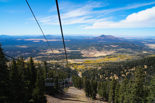 Riding a chair lift over the changing autumn colors of a mountain forest.