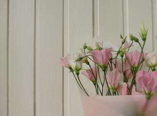 Tender bouquet of eustoma flowers on a white wooden background, closeup
