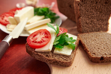 healthy food - fresh bread and feta cheese on a wooden background, tomatoes, greens and vegetables