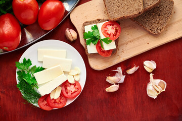 healthy food - fresh bread and feta cheese on a wooden background, tomatoes, greens and vegetables