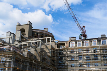 modern building under construction, plastered walls and scaffolding, construction crane