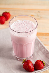 Milkshake with strawberries. Cold summer drink with berries on wooden background.