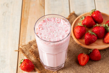 Fresh milkshake with strawberries. Summer drink with berries in a glass on wooden background.