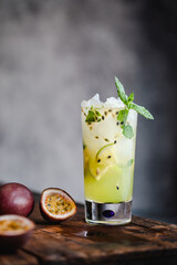 Passion fruit mojito cocktail och mocktail with lime, in a high glass on gray background