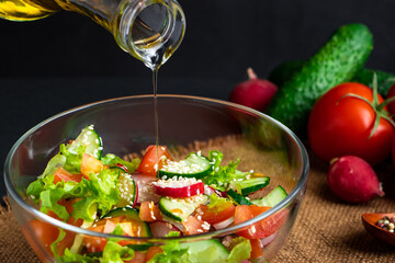 The process of preparing vegetable salad. Seasonal summer dish, vegetarian food on black background.