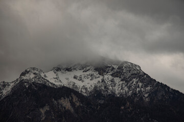 moody dramatic mountain landscape cloudy gray weather day time with Alps mountains snowy peak range