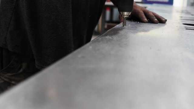 Close-up Shot Of A Worker Drilling A Hole On A Metal Sheet. Close up hand held video as man&rsquo;s hands are drilling holes on a steel sheet.