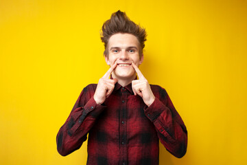 positive guy makes fingers smile on yellow isolated background, man in good mood