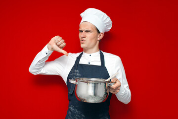 chef in uniform holds a bad dish and shows dislike on a red isolated background, bad smell concept