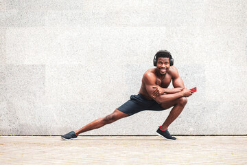 african american sports guy training outdoors against the wall, athletic man doing an exercise...