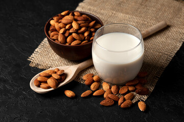 glass of almond milk without lactose and sugar with sprinkled nuts, a veggie milk drink on a black table