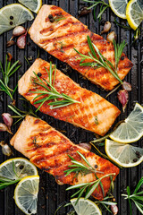 Grilled salmon fillets sprinkled with fresh herbs and lemon juice on a grill top view - 362434366