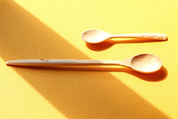 Two wooden spoons of different sizes on a yellow background, top view, place for the inscription-the concept of delicious peasant food in the summer