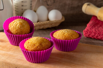 Muffins caseros en molde colorido, con sus ingredientes de fondo para prepararlos,  con foco selectivo. 