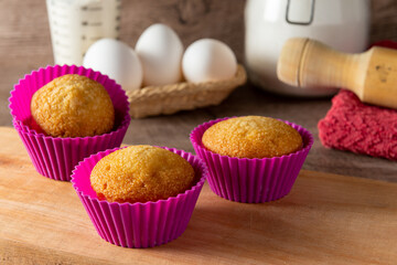 Muffins caseros en molde colorido, con sus ingredientes de fondo para prepararlos,  con foco selectivo. 