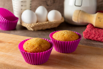 Muffins caseros en molde colorido, con sus ingredientes de fondo para prepararlos,  con foco selectivo. 