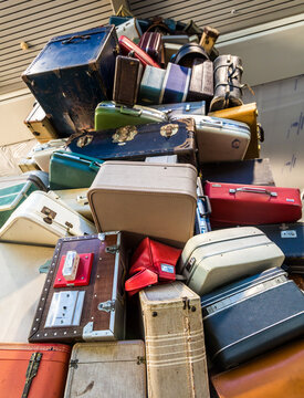 Dramatic Image Of Stacked Colourful Luggage In All Sizes Piled High In A Large Cart. 