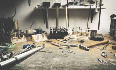Workplace of a jeweler with tools and equipment for working on an old wooden table. Desktop for craft jewelry making with professional tools.