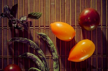Autumn still life - asparagus beans, purple Basil, yellow and chocolate tomatoes on bamboo Mat