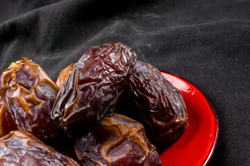 Big luxury dried date fruit in bowls on the dark surface, kurma ramadan kareem concept, close up.