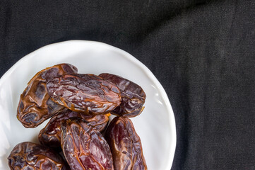 Big luxury dried date fruit in bowls on the dark surface, kurma ramadan kareem concept, close up.