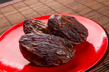 Big luxury dried date fruit in bowls on the bamboo mat, kurma ramadan kareem concept, close up.