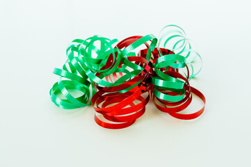 strands of bright red and green Christmas curling ribbon jumbled together isolated on white