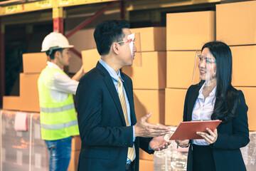 Asian businessperson in protective face shield and engineer in cargo