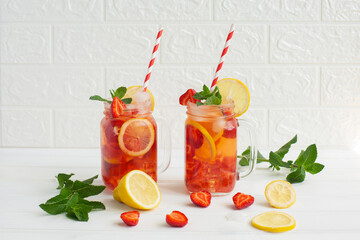 Cold strawberry lemonade juice with ice cubes, lemon and mint.