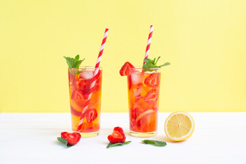 Cold strawberry lemonade juice with ice cubes, lemon and mint.