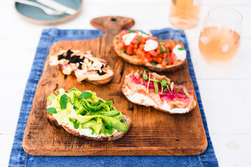 Bruschetta, crostinni, toasts with different toppings on a wood board with rose wine