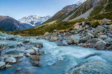 Strong flow of water exiting the Hooker Lake and into the Hooker river that flows through the valley sounded by snow capped Southern Alps in Aoraki Mt Cook National park