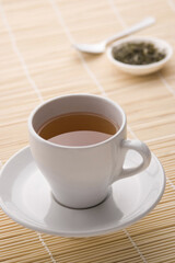 A cup of tea with tea leaves in the background
