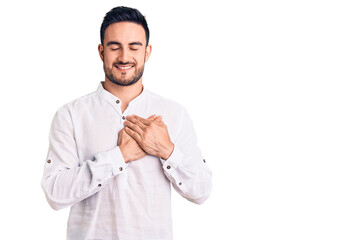 Young handsome man wearing casual clothes smiling with hands on chest with closed eyes and grateful gesture on face. health concept.