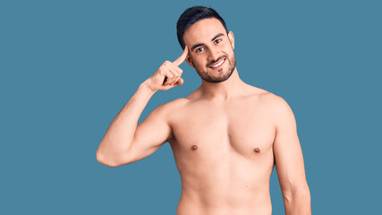 Fototapeta premium Young handsome man wearing swimwear smiling pointing to head with one finger, great idea or thought, good memory