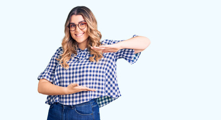 Young caucasian woman wearing casual clothes gesturing with hands showing big and large size sign, measure symbol. smiling looking at the camera. measuring concept.