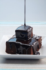 Pouring chocolate syrup onto brownies