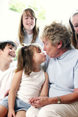 A girl kissing her grandmother whiles her brother and sisters watching