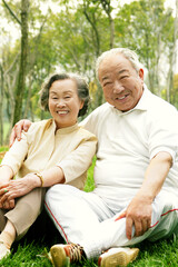 An old couple sitting together on the grass