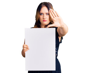 Young beautiful caucasian woman holding cardboard banner with blank space with open hand doing stop sign with serious and confident expression, defense gesture