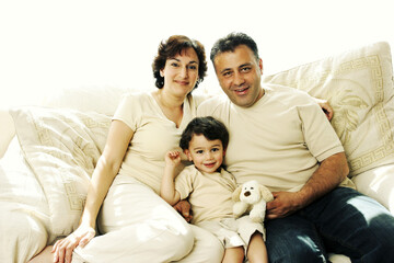 A young boy sitting on the couch with his parents