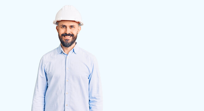 Young handsome man wearing architect hardhat with a happy and cool smile on face. lucky person.