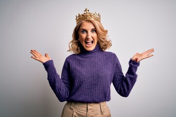 Middle age beautiful blonde woman wearing golden crown of king over white background celebrating...