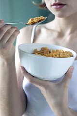 A woman in white camisole eating her breakfast cereal