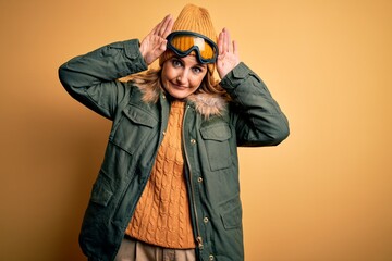 Middle age beautiful blonde skier woman wearing snow sportwear and ski goggles Doing bunny ears gesture with hands palms looking cynical and skeptical. Easter rabbit concept.