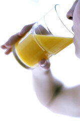 Side shot of a woman drinking a glass of orange juice