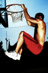 A player hanging onto the hoop after a slam dunk